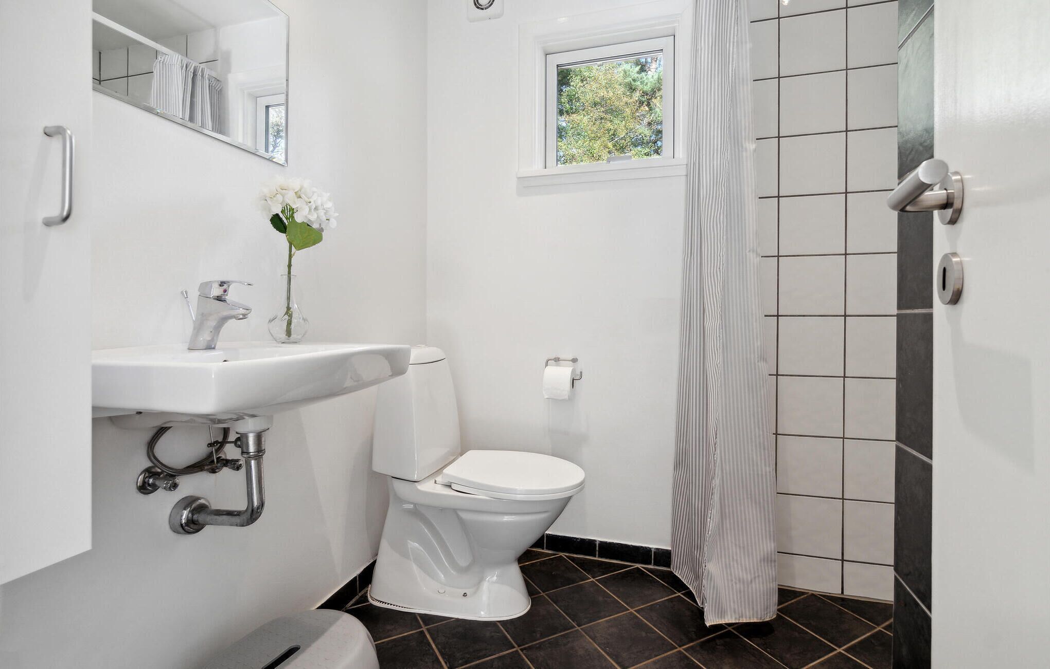 Ein Badezimmer mit weißem Waschbecken, WC und Duschvorhang.