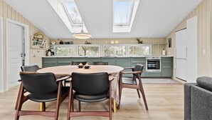 Een moderne keuken met een centraal eiland, dakramen en een eetgedeelte met een ronde tafel en stoelen.