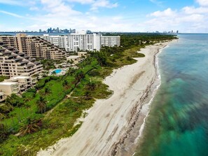A coastal hotel with multiple high-rise buildings, a beach, and a city skyline in the background. - KEY BISCAYNE LUXURY RETREAT - FULLY REMOLEDED 3 BEDROOM 2,000 SF RESIDENCE (Miami)