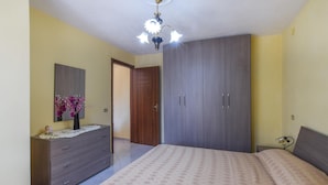 A bedroom with a bed, dresser, wardrobe, and a chandelier.