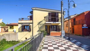A two-story building with a balcony, a checkered pavement in front, and a 20 km/h speed limit sign.