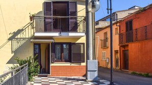 A two-story building with a balcony, a street lamp, and a checkered pavement.