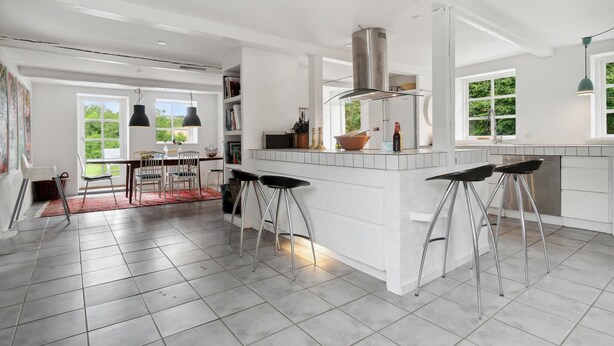 A spacious kitchen with a large island, bar stools, and a dining area with a red rug. - Stunning home in Hasle with WiFi (Hasle)