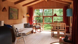 A cozy cabin interior with a wooden floor, a sofa, a rocking chair, and a dining table. - 2 bedroom awesome home in Nexø (Nexø)
