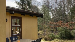 A small, yellow building with a wooden table and chairs outside, surrounded by trees and shrubs. - 2 bedroom awesome home in Nexø (Nexø)