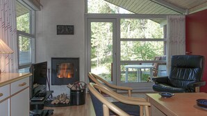 Un salon chaleureux avec une cheminée, des meubles en bois et une vue sur l’extérieur.