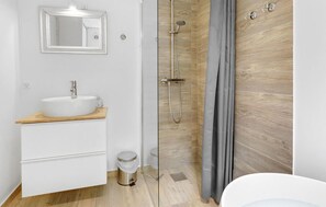 A modern bathroom with a white sink, wooden countertop, and a glass shower enclosure. - Amazing home in Aakirkeby (Aakirkeby)
