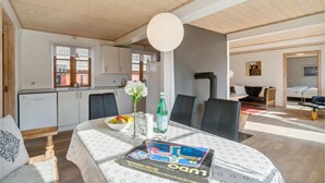 A modern kitchen with wooden cabinets, a dining table with a board game, and a living area with a sofa and a bed. - 2 bedroom awesome home in Nexø (Nexø)