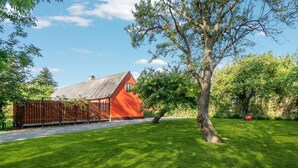 A red house with a sloped roof, surrounded by a wooden fence and a well-maintained lawn. - 2 bedroom awesome home in Nexø (Nexø)