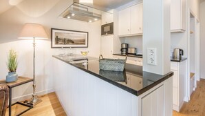 A modern kitchen with a central island, white cabinetry, and a pendant light. - Witthüs, Whg. 19 - Witthüs (Wenningstedt-Braderup (Sylt))