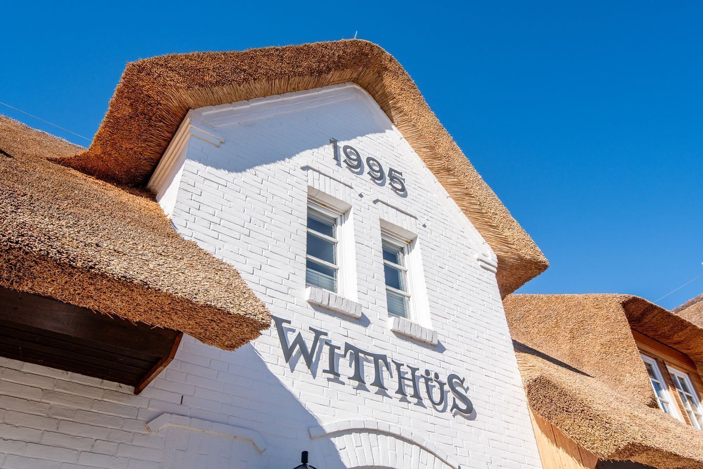 A building with a white facade, the year 1995, and the name 'WITHHUS' on the side.