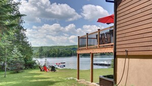 Une terrasse avec vue sur un lac et un quai, entourée d’arbres.