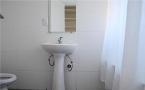 Bathroom features a pedestal sink, mirror, and toilet, with a shower curtain.