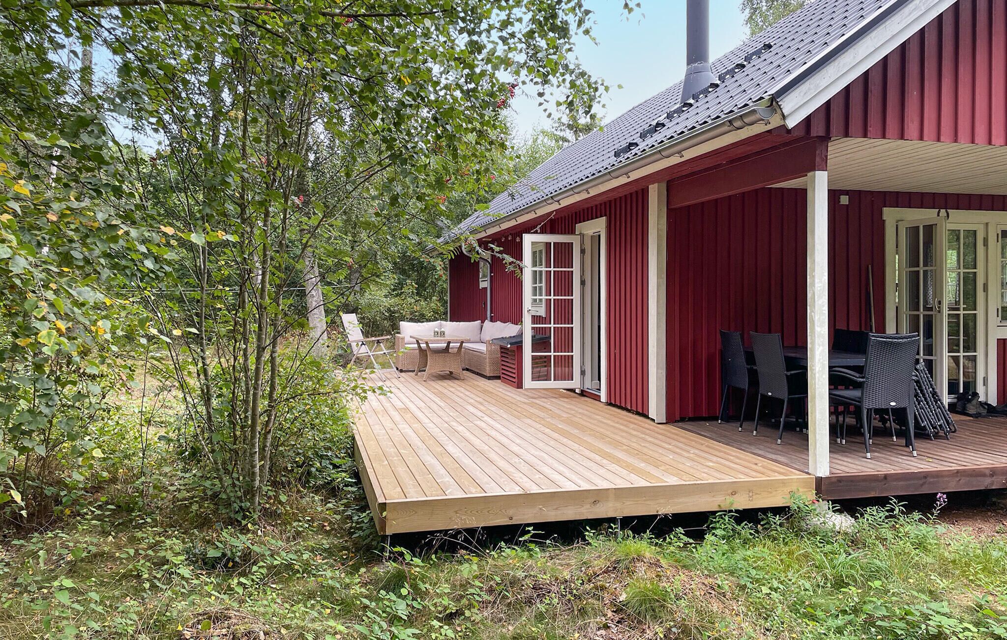 Une cabane en bois rouge avec une terrasse, un canapé et une table.