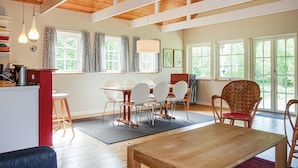 A spacious room with a wooden ceiling, large windows, a dining area with white chairs, and a wooden table. - Amazing home in Hasle with kitchen (Hasle)