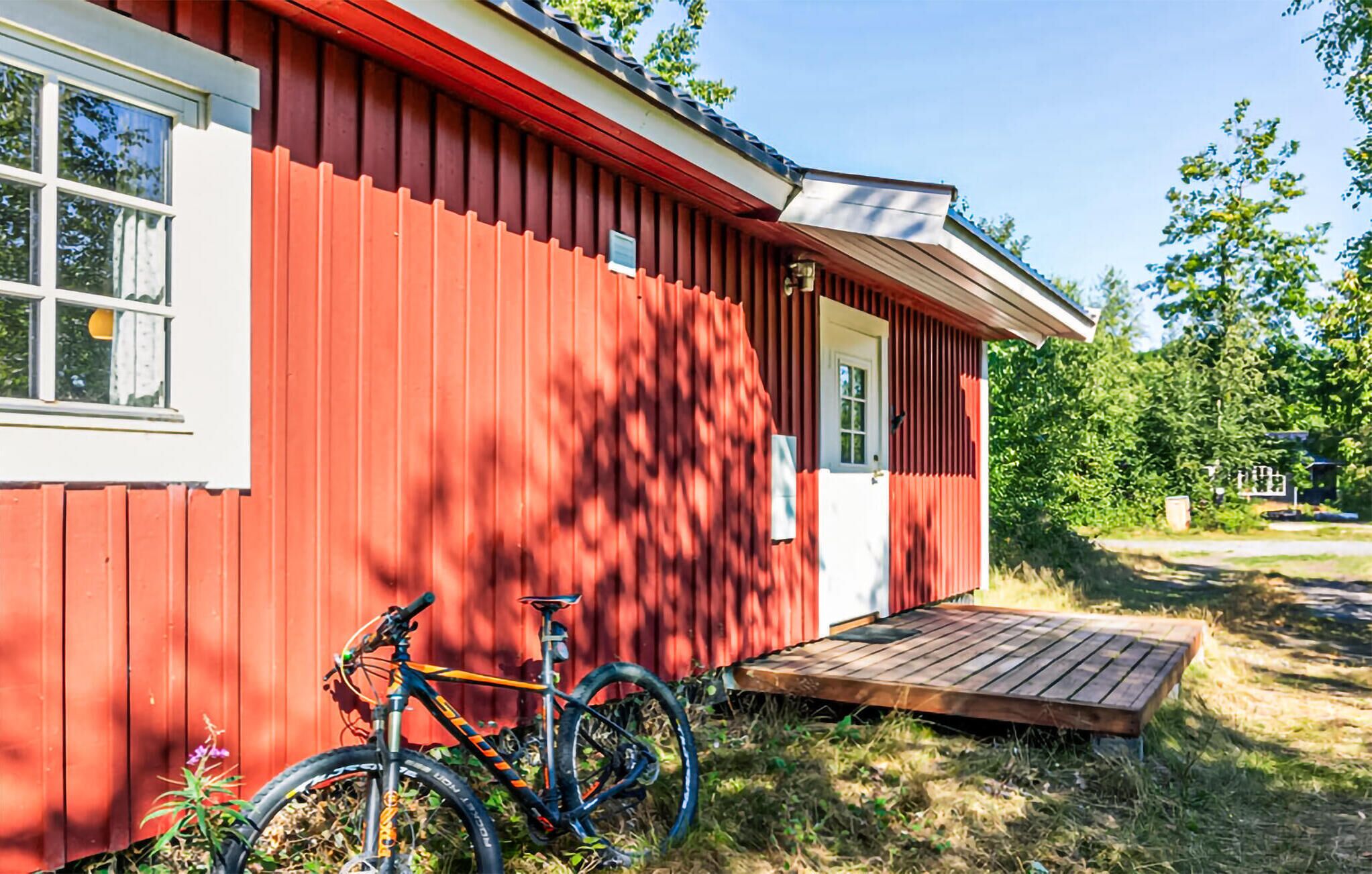 Ein rotes Holzhaus mit einer kleinen Veranda und einem Fahrrad davor.