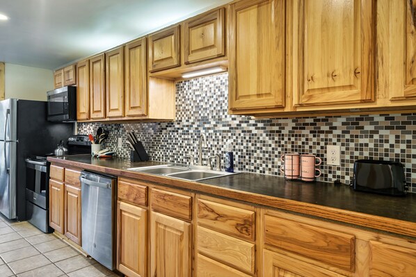 Kitchen features a stainless steel refrigerator, dishwasher, sink, and toaster.