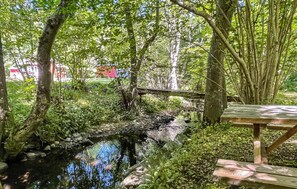 A natural setting with a small stream, wooden bridge, and picnic table. - 2 bedroom beautiful home in Rønne (Rønne)