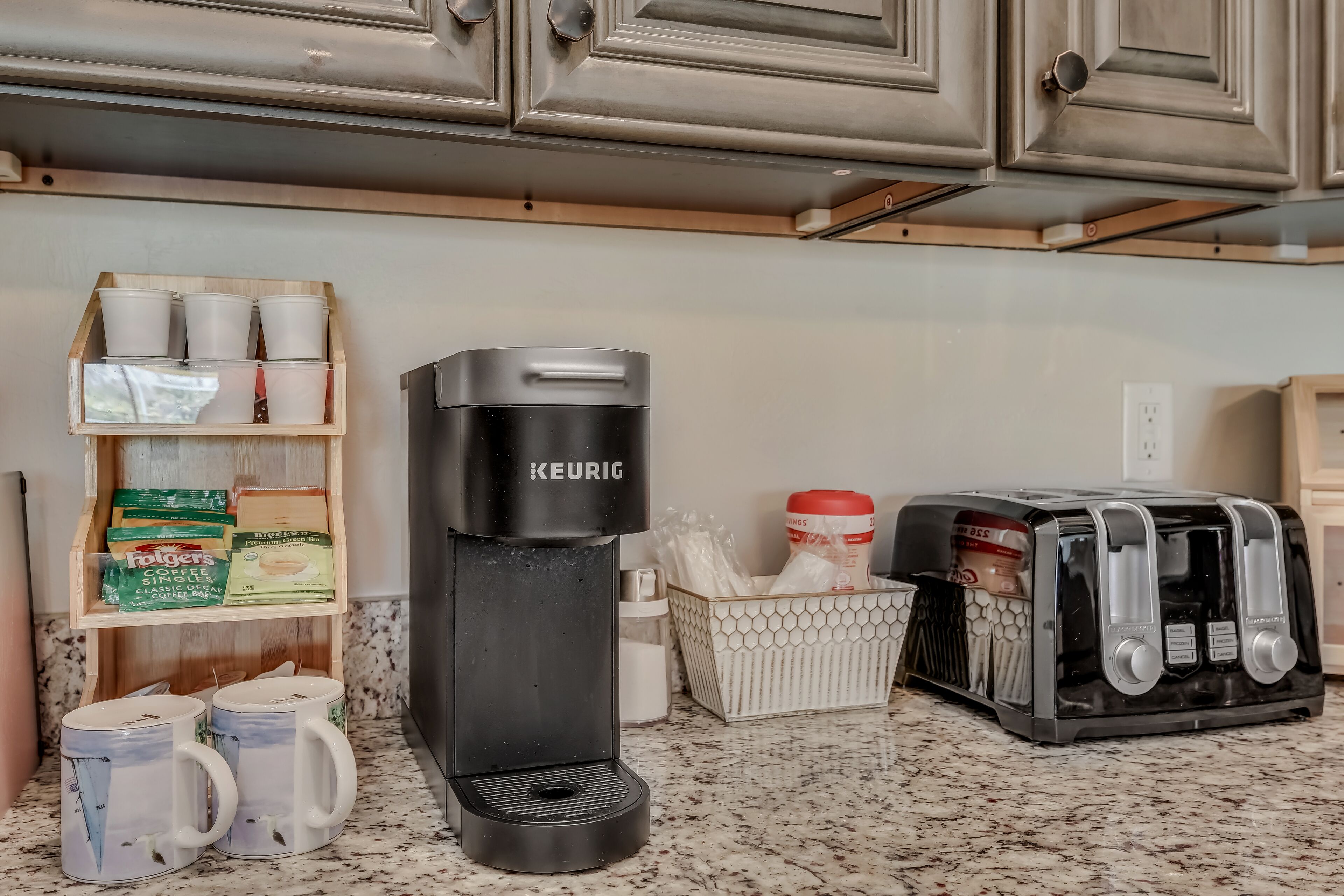 Een keuken met een Keurig koffiezetapparaat, een broodrooster en een plank met koffiebonen.