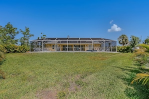 A two-story building with a covered outdoor area, surrounded by grass and trees.