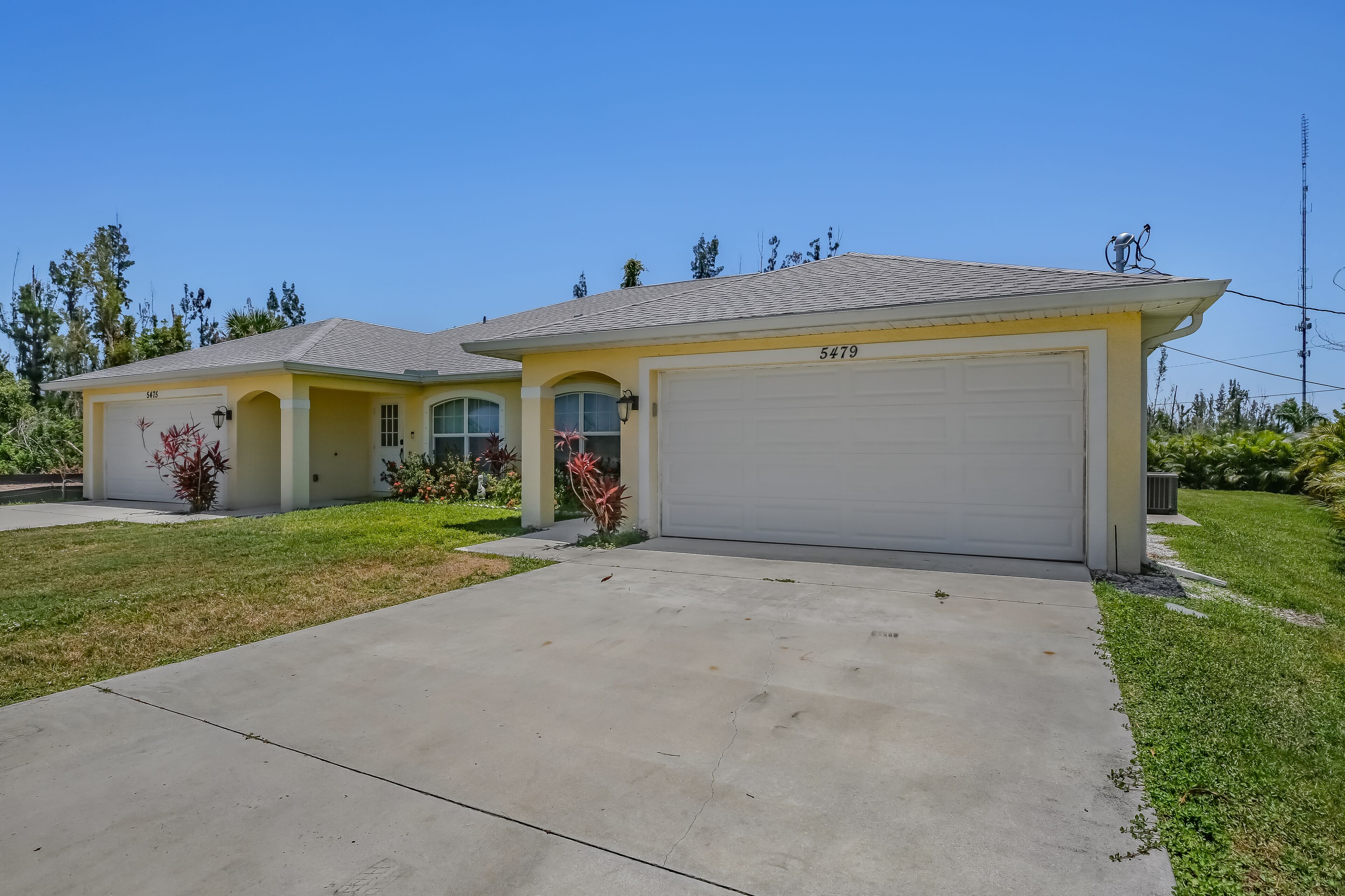 A two-story residential house with a garage numbered 5479, a well-maintained lawn, and a clear sky.