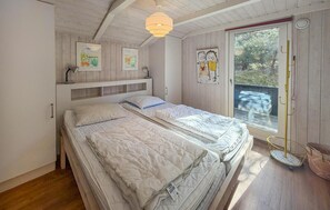 A bedroom with a bed, a window, and artwork on the wall.