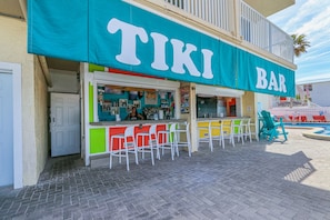 A tiki bar with outdoor seating and a pool.