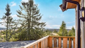Eine Holzterrasse mit Blick auf einen Wald und ferne Hügel.