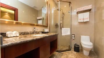 Un baño moderno con ducha envuelta en vidrio, lavamanos de mármol y un inodoro.