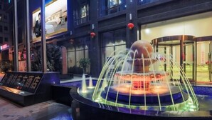Un hotel moderno con una fontana centrale, un ingresso in vetro e una insegna.