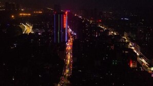 Panorama notturno di una città con edifici illuminati e una strada trafficata.