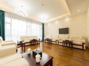 A spacious living room with a large sofa set, a coffee table, and a flat-screen TV mounted on the wall. - Greentree Eastern Yibin Yijian Road New City Plaza Hotel (Yibin)