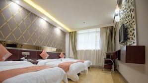 Habitación de hotel con tres camas, televisión, escritorio y ventana con cortinas.