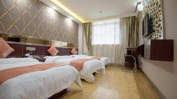 A hotel room with three beds, a TV, a desk, and a window with curtains.