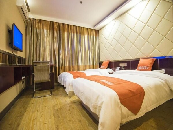 Habitación de hotel con dos camas, televisión, escritorio y ventana con cortinas.