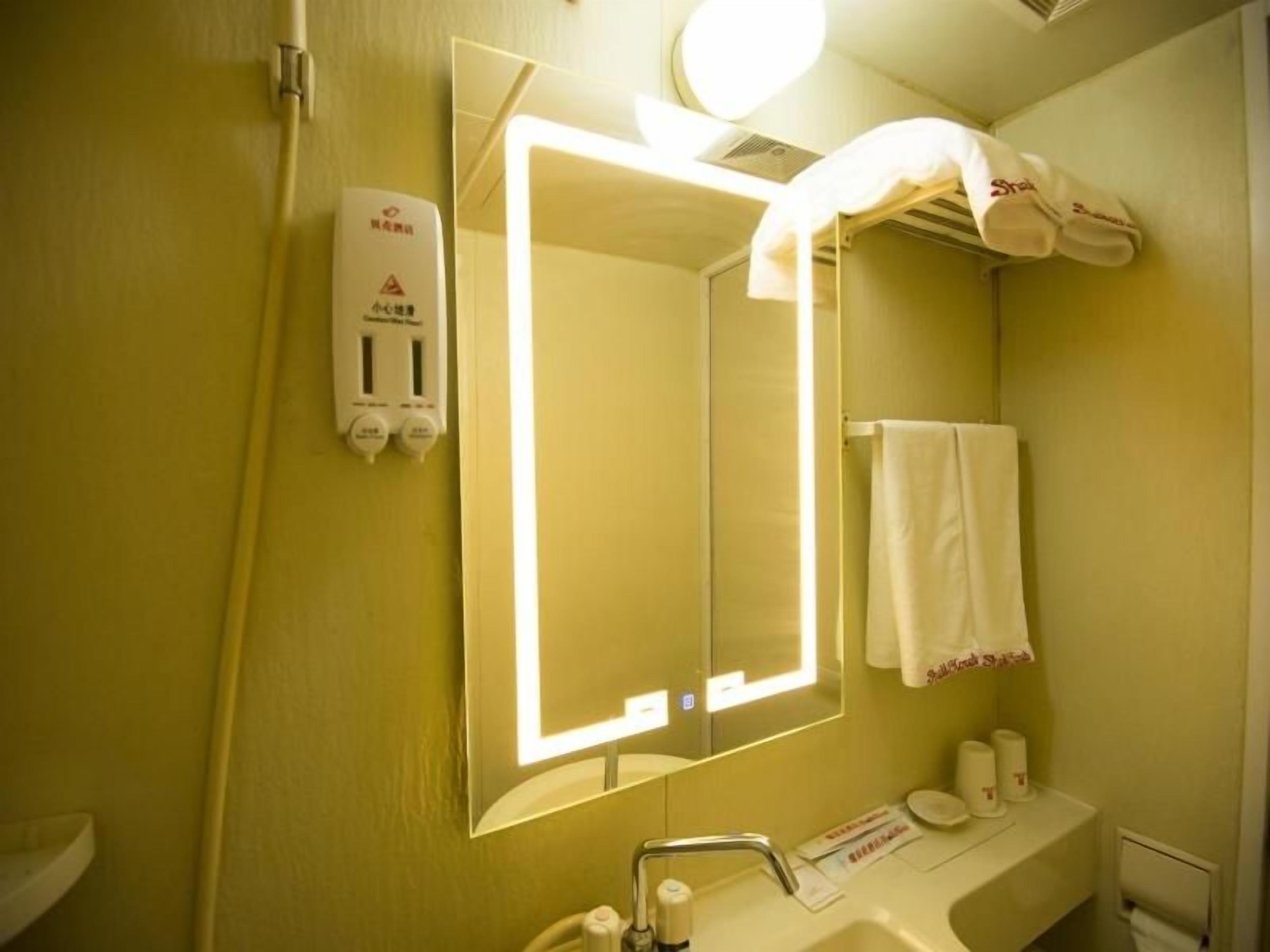A bathroom with a mirror, sink, towel rack, and a hand dryer.