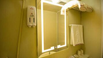 A bathroom with a mirror, sink, towel rack, and a hand dryer.