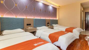 A hotel room with three beds, each with a white and orange bedspread, and a modern headboard design.