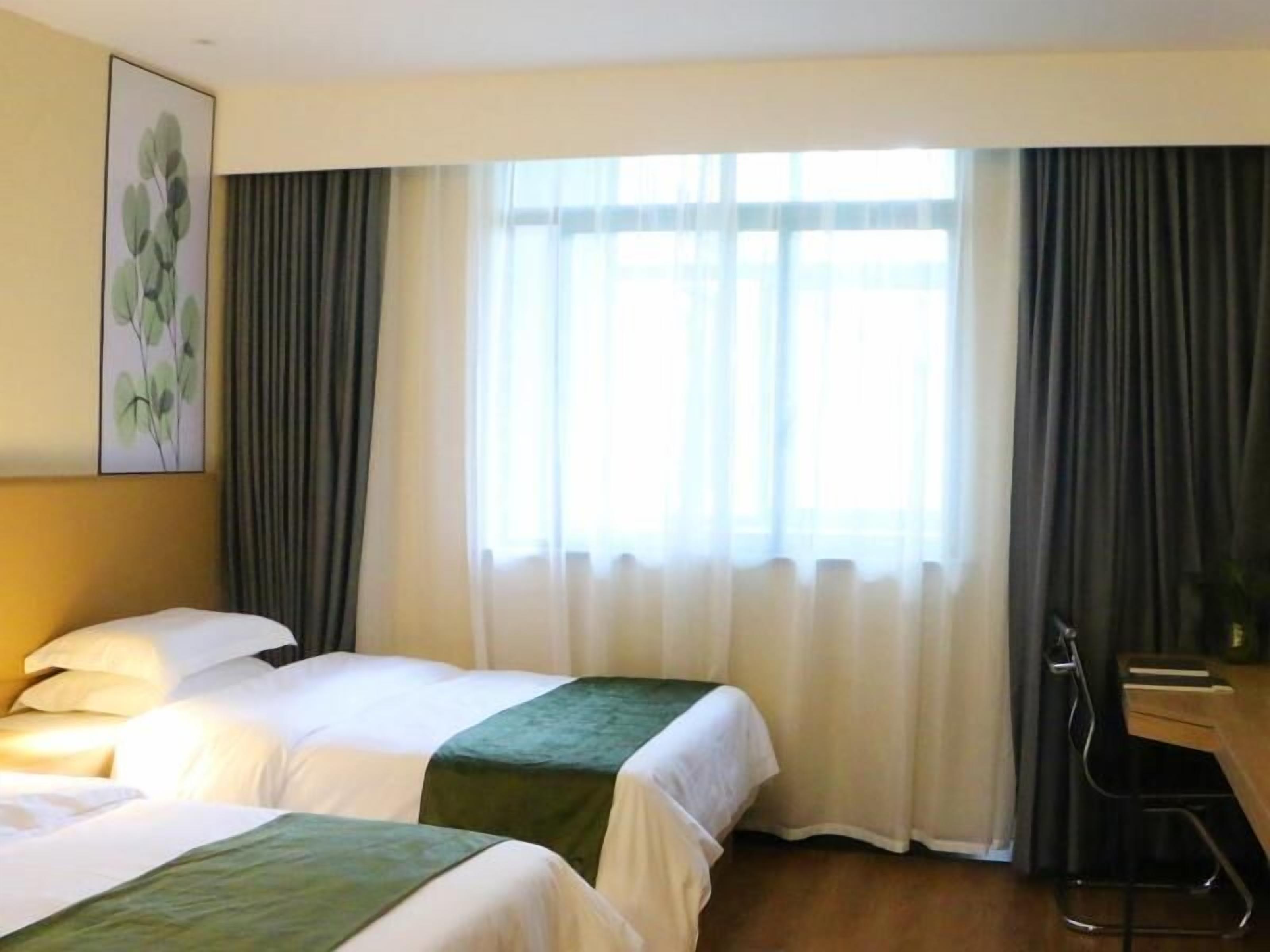 A hotel room with two beds, a desk, and a chair.