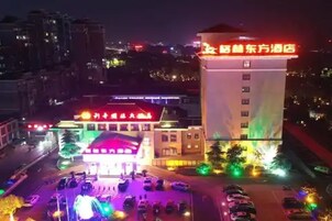 Un hotel con un letrero rojo llamativo, un estacionamiento con varios autos y un edificio de varios pisos.