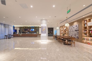 A spacious lobby with a reception desk, a dining area with tables and chairs, and a bookshelf filled with books. - Greentree Inn Jinan Tangye Express Hotel (Jinan)