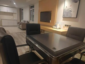 Ein modernes Wohnzimmer mit Esstisch, Stühlen, einer Couch, einem Fernseher und einer Kaffeemaschine.