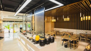 Un interno ristorante moderno con un'area buffet, soffitto in legno e lampadari a sospensione.