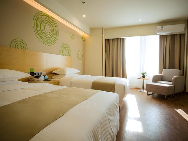 A hotel room with two beds, a small table with a plant, a chair, and a large window with curtains.