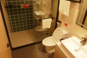 Un baño pequeño y funcional con cabina de ducha de vidrio, inodoro y lavamanos.