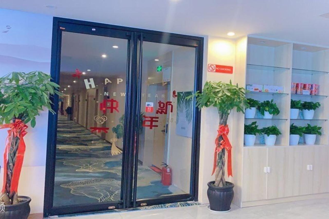 Een hotelentree met een glazen deur, rode decoraties en binnenplanten.