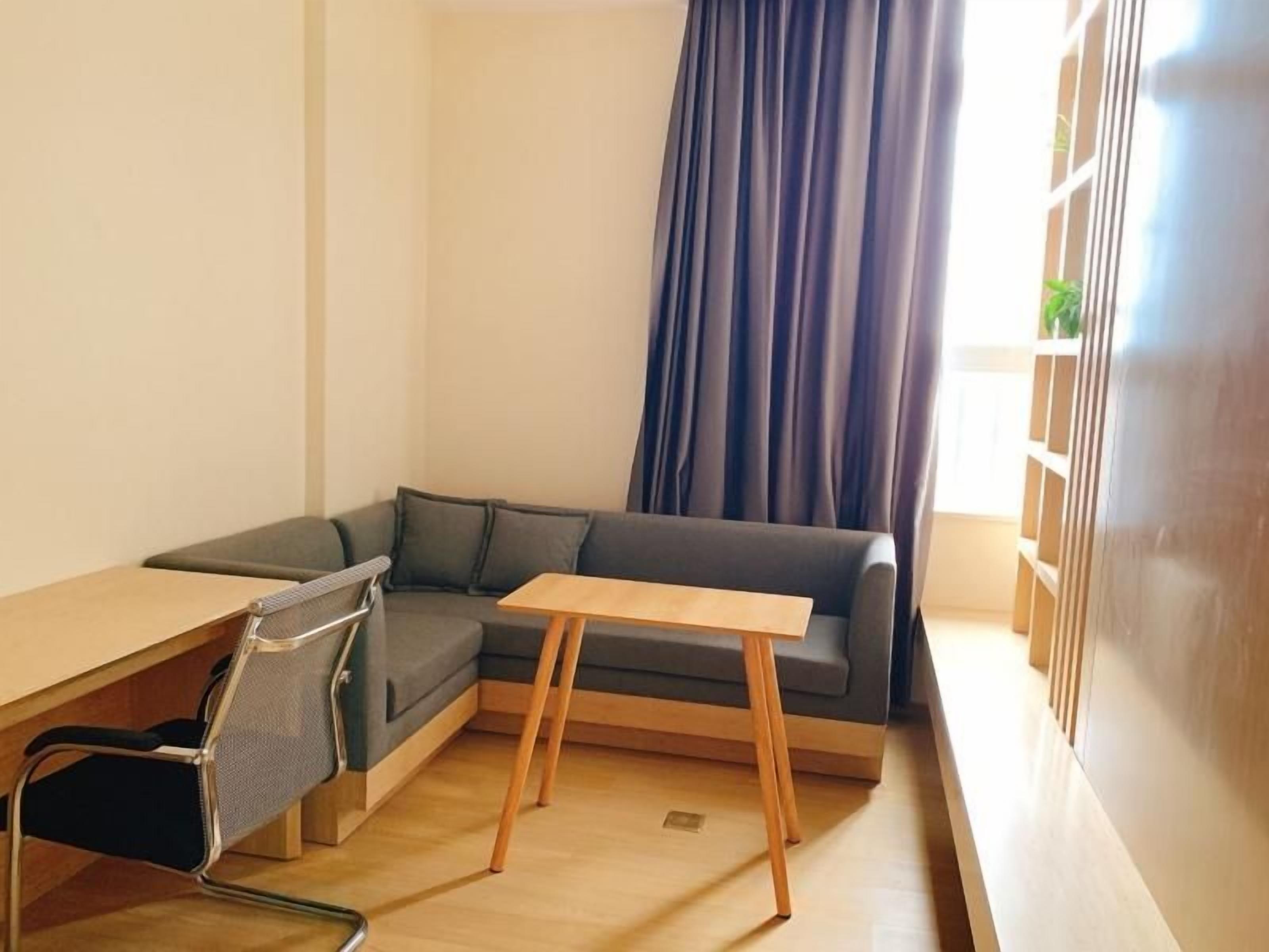 A modern room with a grey sofa, a wooden table, and a mesh chair.