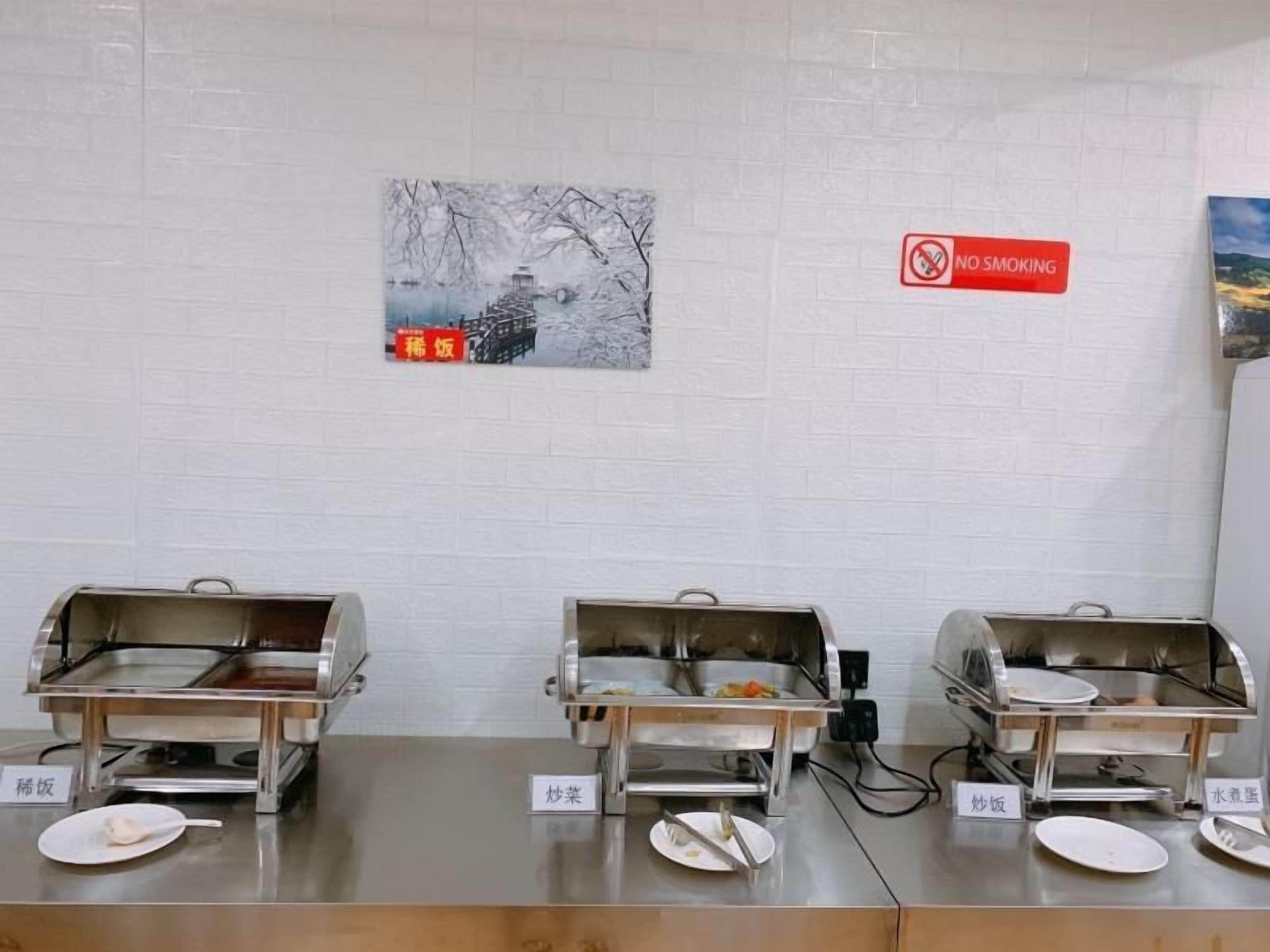 A buffet setup with labeled food stations, a no-smoking sign, and a wall-mounted picture.
