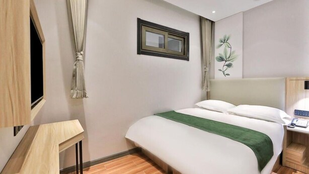 A hotel room with a bed, a TV, a bedside table, and a wall-mounted picture. - Greentree Inn Beijing Dongcheng District Beixinqiao Subway Station Guijie Street Express Hotel (Beijing)