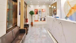 A hotel reception area with a marble reception desk, a brown leather sofa, and a potted plant. - Greentree Inn Beijing Dongcheng District Beixinqiao Subway Station Guijie Street Express Hotel (Beijing)